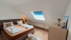 Une chambre à coucher avec un lit, une table de chevet, une lampe et une lucarne.