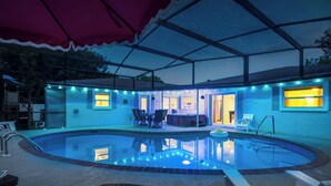 Et poolområde med overdækket terrasse, liggestole og bar.