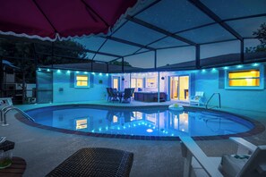Ein Poolbereich mit überdachter Terrasse, Liegestühlen und Bar.