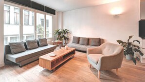 Un salon moderne avec un canapé, un fauteuil, une table basse et des plantes en pot.