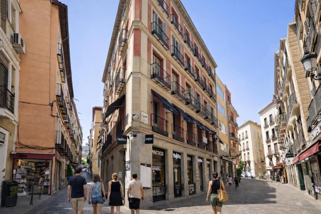 A street with multi-story buildings, shops, and pedestrians.