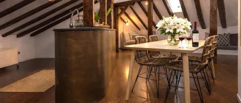 Un comedor con una mesa de madera, sillas de mimbre, una isla central y una lámpara colgante.