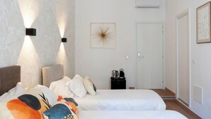 Un dormitorio con dos camas, una cafetera y un cuadro en la pared.