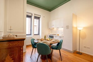 Ein Essbereich mit einem Tisch für vier Personen, einem Holzkabinett mit Zierelementen und einer Stehlampe.