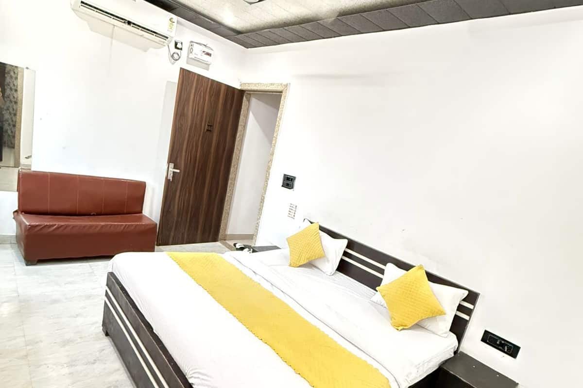 Un dormitorio con una cama, un sillón de cuero marrón, una puerta de madera y un ventilador de techo.