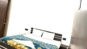 A bedroom with a bed, a ceiling fan, and a door. - Vidya Dham Vrindavan  (Vrindavan)