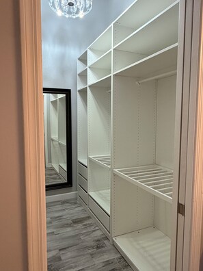 Ein begehbarer Kleiderschrank mit offenen Regalen und einer Spiegeltür.