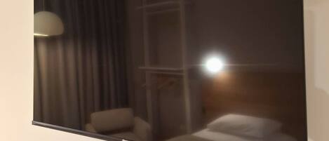 A room with a bed, a chair, a lamp, and a window.