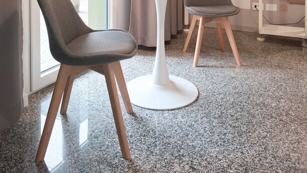A modern room with a round table, two chairs, a vase with flowers, a hanging light fixture, and a wardrobe with hangers. - Eva Urban Rooms Centro Lecco (Lecco)