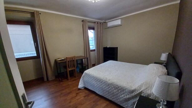 A bedroom with a bed, a desk, a chair, a lamp, and an air conditioning unit. - Large master bedroom with private bathroom (Friuli-Venezia Giulia)