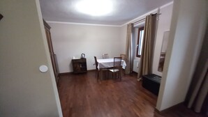 A room with a wooden floor, a dining table with chairs, a small cabinet, and a radiator. - Large master bedroom with private bathroom (Friuli-Venezia Giulia)