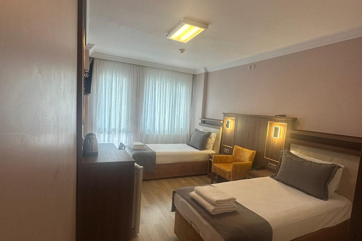 Una habitación de hotel con una cama, un escritorio, una silla y un ventanal con cortinas.