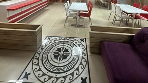 Un restaurante con zona de estar central, mostrador de diseño rojo y blanco, y un mural decorativo en la pared.