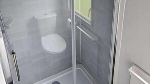 A glass-enclosed shower stall with a toilet and a drain. - Cabin Sleeps 6 With Wifi (Skegness)