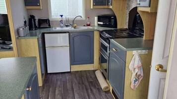 Una cocina compacta con refrigerador, microondas y estufa.