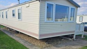 A mobile home with a single window, a chimney, and a small porch. - Cabin Sleeps 6 With Wifi (Skegness)
