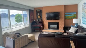 Ein Wohnzimmer mit Kamin, Fernseher und Seeblick.