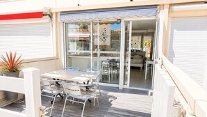 Ein zweistöckiges Gebäude mit Balkon, Glastür und einer Terrasse mit Tisch und Stühlen.