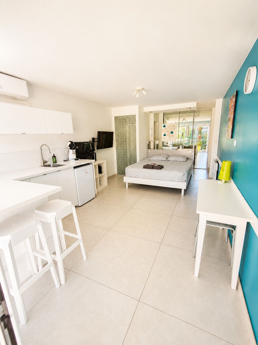 A modern, well-lit room with a kitchen, a bed, and a dining area.