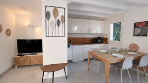 Una cucina moderna con mobili bianchi, un tavolo da pranzo in legno e un televisore a schermo piatto.