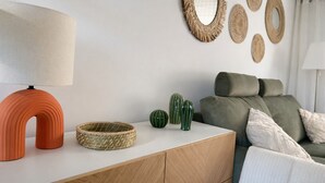 Un soggiorno moderno con un divano, una lampada, specchi decorativi e una piccola collezione di cactus.