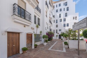Une rue étroite bordée de bâtiments blancs, une porte en bois et une enseigne indiquant « Sky Lounge ».