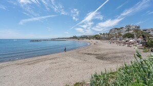 A beach with a clear sky, a sandy shore, and a distant building complex. - Holiday Home 'Enjoy Puerto Banus Next To Beach' with Sea View, Wi-Fi and Air Conditioning (Marbella)