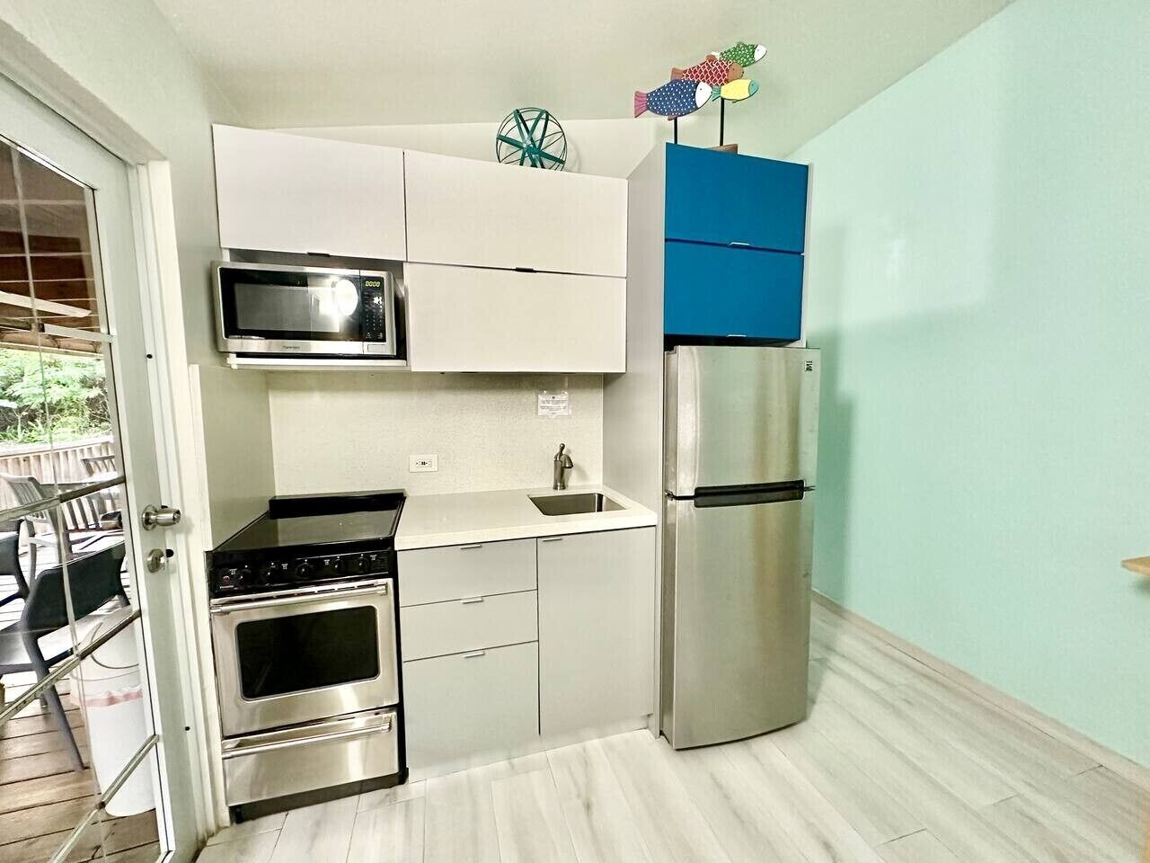 A compact kitchen with a microwave, stove, sink, and refrigerator.