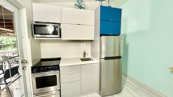 A compact kitchen with a microwave, stove, sink, and refrigerator.