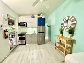 A compact kitchen with a microwave, oven, and refrigerator, a wooden table with plants, and a ceiling fan. - Villa 11 Flamenco Beachfront Villa (Flamenco)