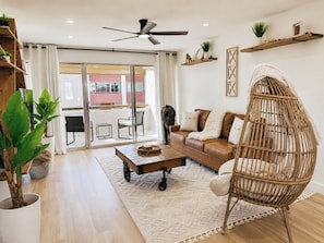 A living room with a brown sofa, a wicker chair, a coffee table, and a ceiling fan. - Beautiful 1 Bedroom Sun Lit Scottsdale Condo Welcome To Old Town Scottsdale (Scottsdale)