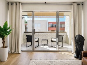 A modern living room with a sliding glass door leading to a balcony, a potted plant, a sculpture, and a brown leather sofa. - Beautiful 1 Bedroom Sun Lit Scottsdale Condo Welcome To Old Town Scottsdale (Scottsdale)