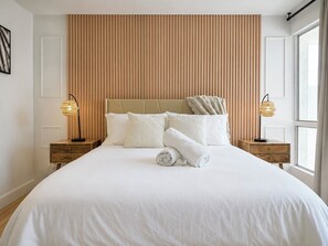 Una camera d'albergo con un letto grande, due comodini, una testiera e una finestra.