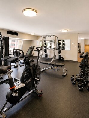 Ein Fitnessraum mit Laufbändern, Krafttrainingsgeräten und Kurzhanteln.