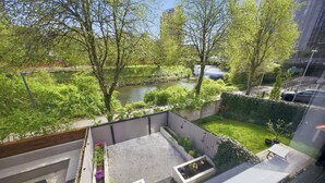 Un jardín en la azotea con vistas a un río, una terraza de madera y un pequeño rincón de estar.