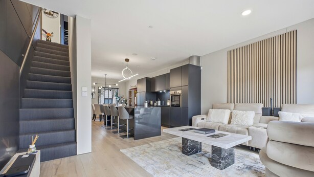 Una sala de estar moderna con escalera, comedor y cocina.