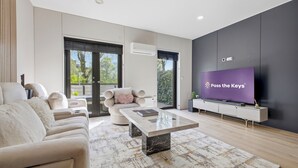 Una sala de estar moderna con sofá, mesa de centro, televisor y un ventanal grande.