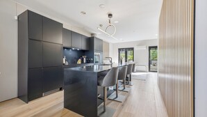 Una cocina moderna con armarios oscuros, una isla central y taburetes de bar.