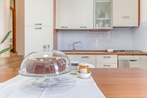 A kitchen with white cabinets, a wooden countertop, a glass cake stand, and two jars of jam. - Apartment 'Casa Buongiorno Salento' with Private Terrace, Wi-Fi and Air Conditioning (Patù)