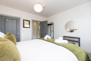 Une chambre d’hôtel avec un lit, une douche, un miroir et une œuvre d’art encadrée au mur.