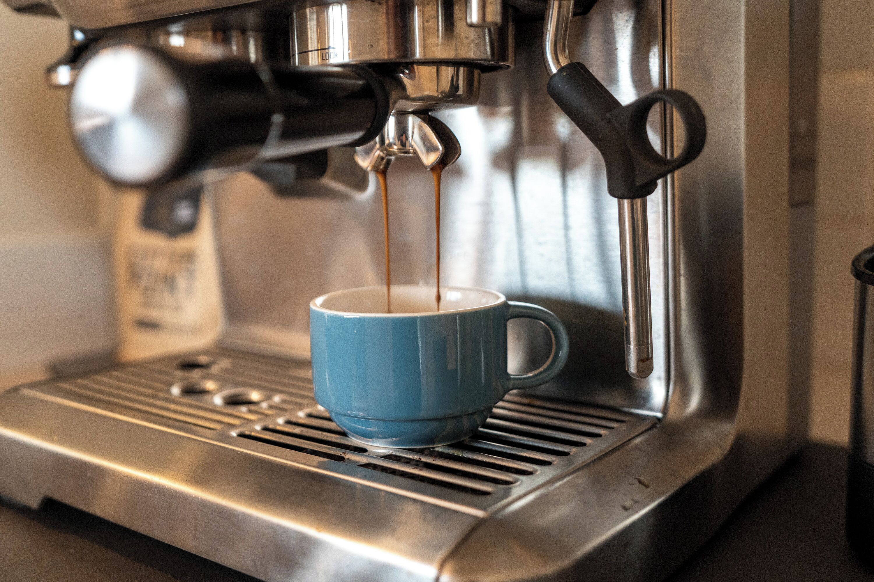 Eine Kaffeemaschine füllt einen blauen Becher mit Kaffee.