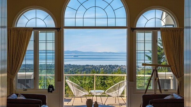 A room with a large arched window, a telescope, and two chairs. - Mountain Estate | Pickleball, Hot Tub, Game Room (Port Angeles)