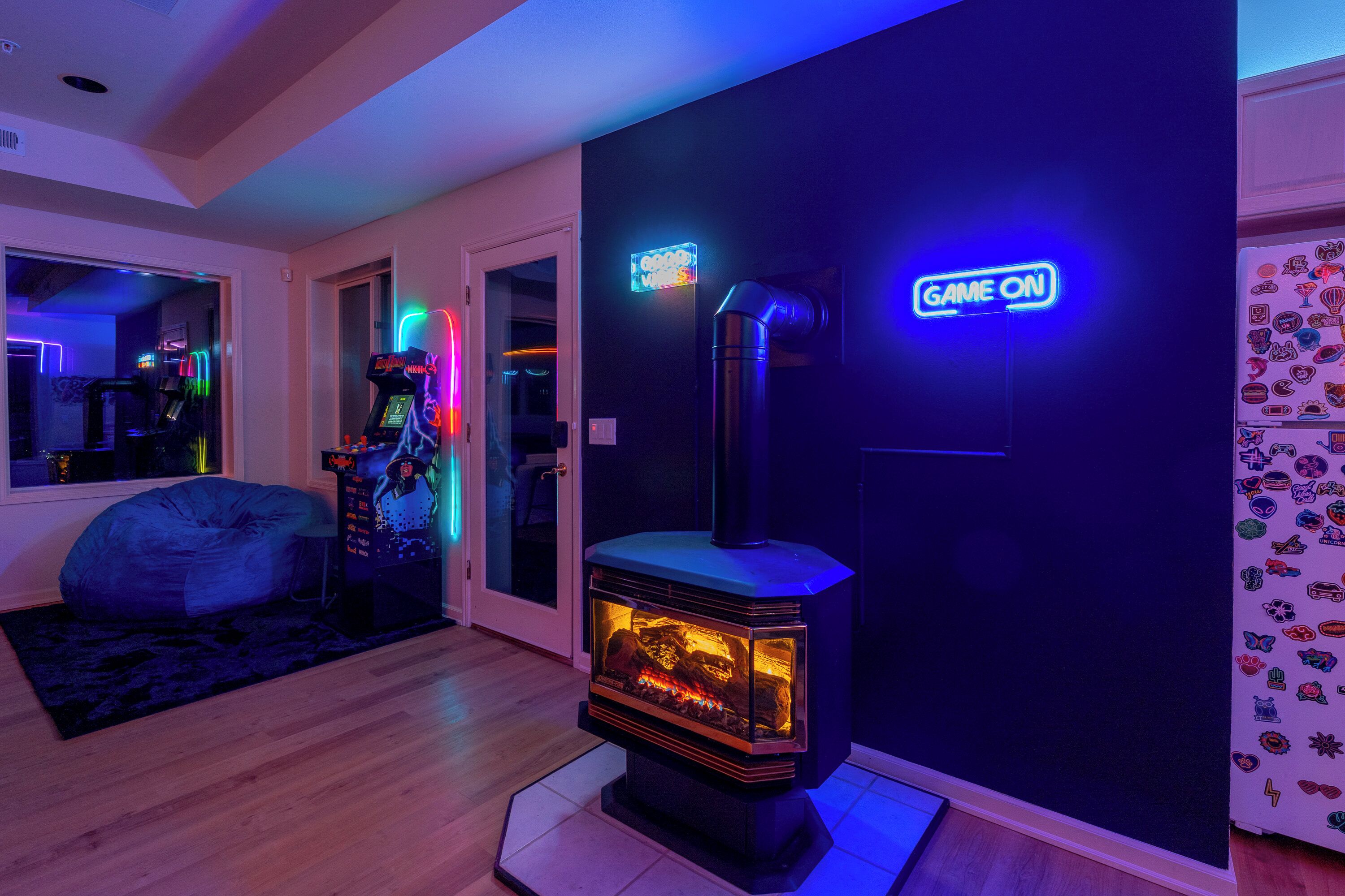 A room with a wood-burning stove, neon signs, and a bean bag chair.