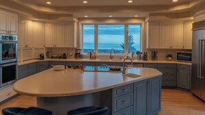 A modern kitchen with a large island, built-in appliances, and a view through the windows. - Mountain Estate | Pickleball, Hot Tub, Game Room (Port Angeles)