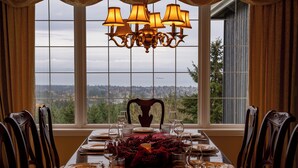 A dining table set for six with a view of a cityscape through large windows. - Mountain Estate | Pickleball, Hot Tub, Game Room (Port Angeles)