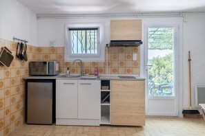 A compact kitchen with a built-in microwave, sink, and storage cabinets.
