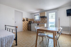 A compact kitchen with a dining table, chairs, and a bed in the adjacent room.