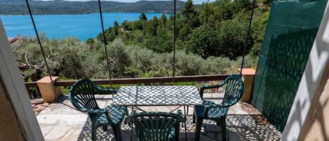A patio with a table and chairs, overlooking a lake and hills.