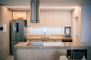 Eine moderne Küche mit einem Edelstahl-Kühlschrank, einem Einbauofen und einer Arbeitsplatte aus Granit.