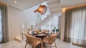 Un comedor moderno con una mesa redonda, sillas de mimbre y una lámpara de techo original.